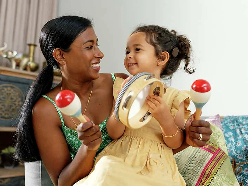 Cochlear ஒலி செயலி அணிந்த ஒரு சிறுமி, தன் தாயுடன் இசைக்கருவிகளை வாசித்துச் சிரிக்கிறாள்