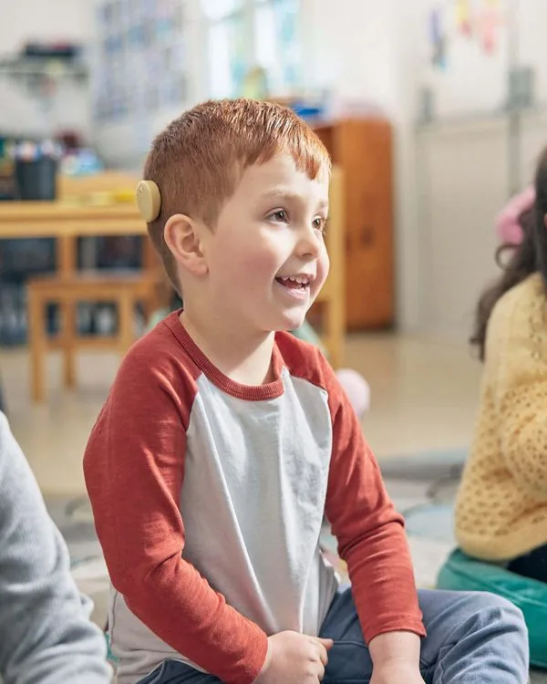 A young boy smiling in a classroom