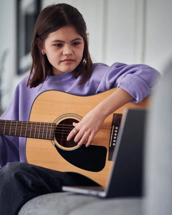 A girl playing an acoustic guitar at home