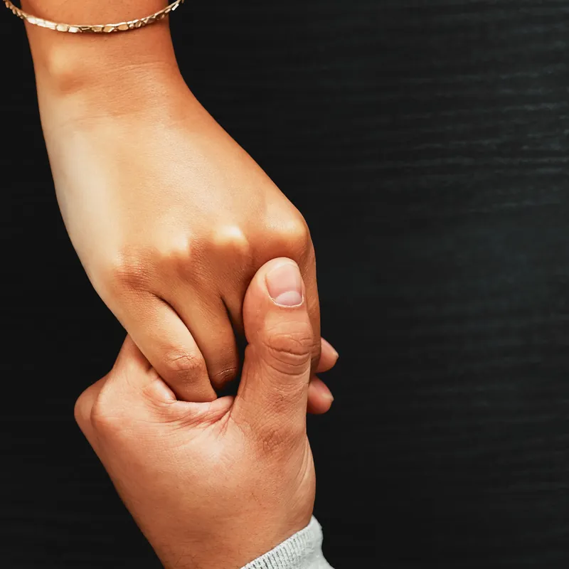 A parent holding a young child's hand